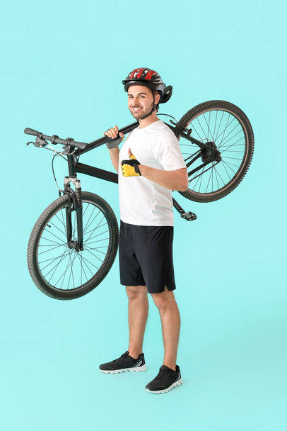 Male cyclist with bicycle showing thumb-up on color background - Photo, Image