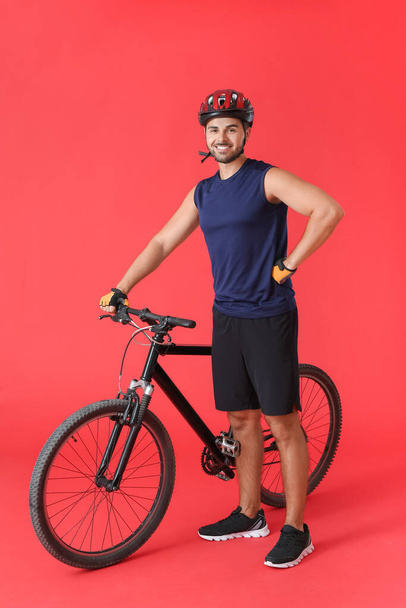 Male cyclist with bicycle on color background - Photo, Image