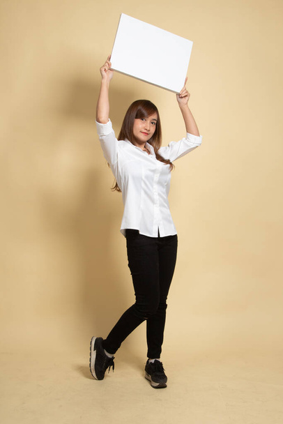 Young Asian woman with white blank sign on beige background - Fotó, kép