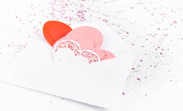Carta de amor, sobre con corazones artesanales de papel sobre fondo con confeti - Foto, Imagen