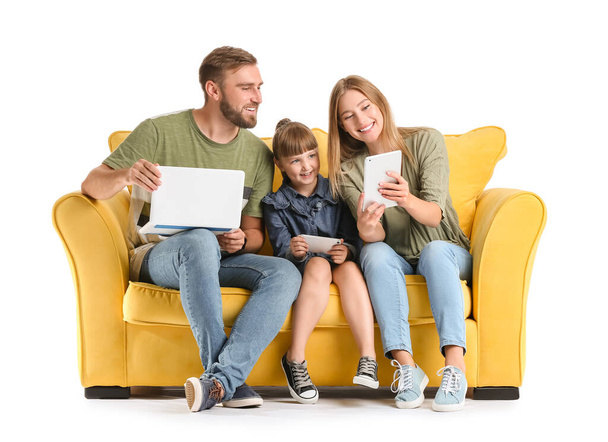 Ευτυχισμένη οικογένεια με gadgets στον καναπέ σε λευκό φόντο - Φωτογραφία, εικόνα