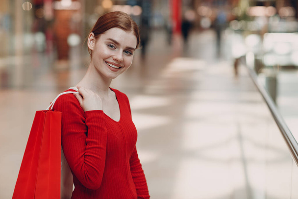 Mujer joven con bolsas rojas de papel en el centro comercial. Viernes Negro y San Valentín concepto de día - Foto, imagen
