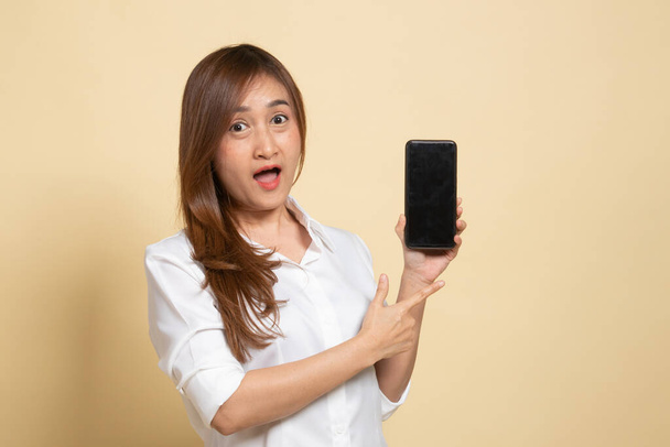 Excited Young Asian woman point to mobile phone on beige background - Φωτογραφία, εικόνα