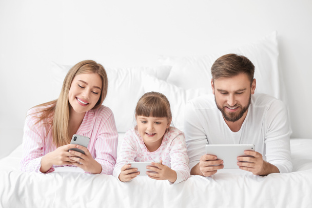 Glückliche Familie mit Mobiltelefonen im Schlafzimmer - Foto, Bild