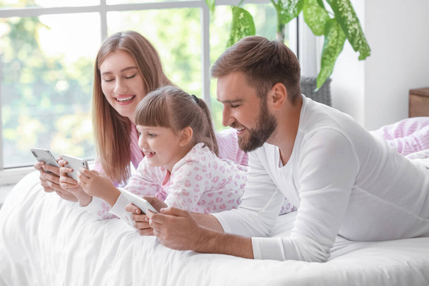 Famiglia felice con telefoni cellulari in camera da letto - Foto, immagini