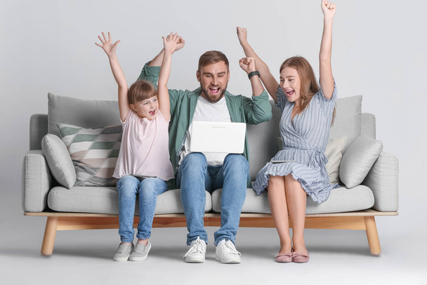 Famiglia felice con laptop moderno su divano su sfondo chiaro - Foto, immagini