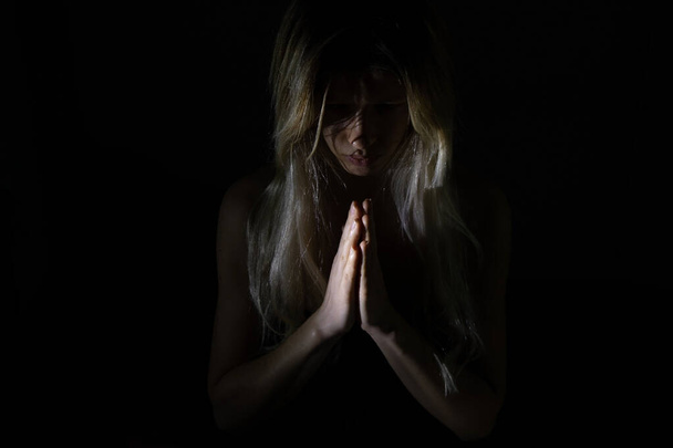 dívka ve tmě se slabým světlem modlí k Bohu, doufat v nejlepší - Fotografie, Obrázek