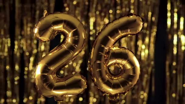 Arany szám 26-26, felfújható lufiból készült, sárga háttérrel. Egyike a teljes számoknak. A születésnap, évforduló, dátum fogalma - Felvétel, videó