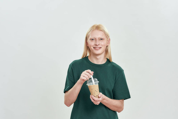 Happy young man holding cup with latte and smiling - Valokuva, kuva
