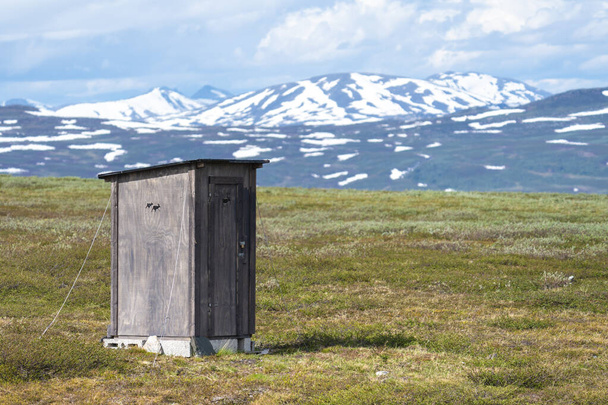 Plumpsklo mit Rentiersymbol, das von den Ureinwohnern des Padjelanta-Nationalparks in Schwedisch Lappland verwendet wird, mit offener Landschaft und Gebirgszug in der Ferne. - Foto, Bild