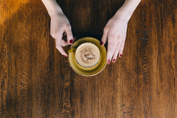 Τα χέρια του κοριτσιού κρατούν την κούπα του καφέ. επίπεδο lay, πάνω όψη - Φωτογραφία, εικόνα