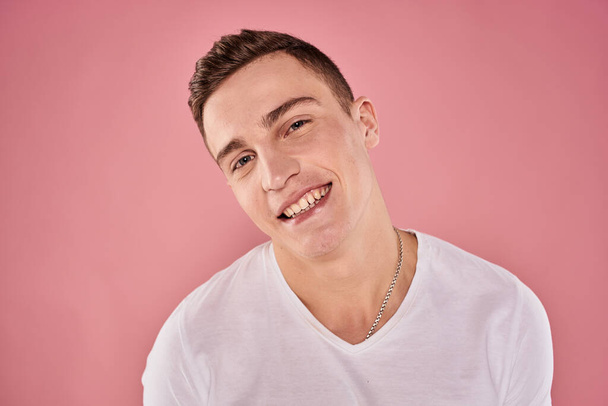 vidám férfi fehér póló mosoly érzelmek közelkép rózsaszín háttér stúdió - Fotó, kép