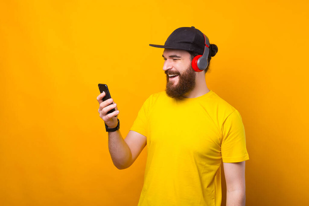 Um homem barbudo feliz está falando com seu telefone e está ouvindo a música ao mesmo tempo - Foto, Imagem
