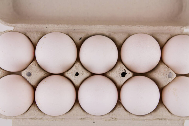 a fresh raw chicken eggs in a cardboard tray on a white background - Foto, Bild