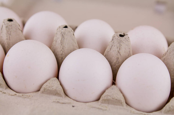 a fresh raw chicken eggs in a cardboard tray on a white background - Foto, Bild