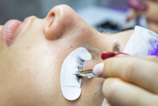 woman at spa salon applying false eyelashes - Foto, Imagen