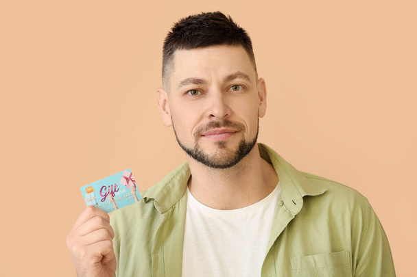 Handsome man with gift card on color background - Foto, Bild