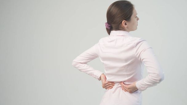 Väsynyt nainen tuntee niskakipua, hierovat jännittyneitä lihaksia. selkäkipu ja alaselän näkymä - Valokuva, kuva