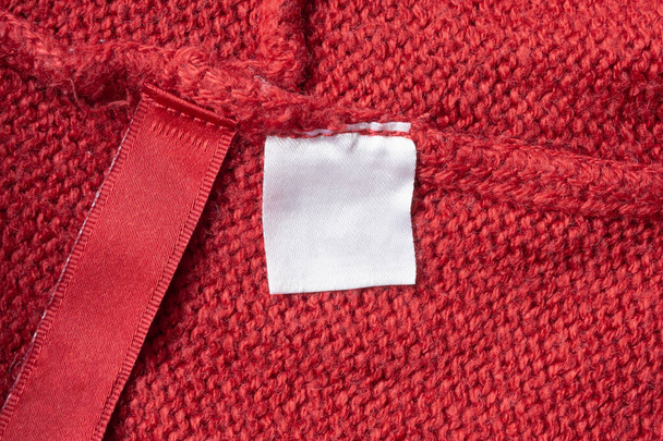 Etiqueta de ropa de lavado en blanco sobre fondo de textura de tela de punto rojo - Foto, imagen
