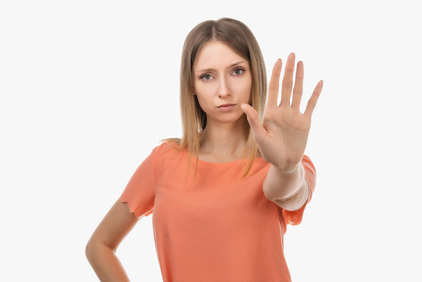 I say no. Serious blond girl keeps palm forward at camera, makes forbid sign, restricts or warns, extends arm in stop sign. Studio shot, white background - Photo, Image