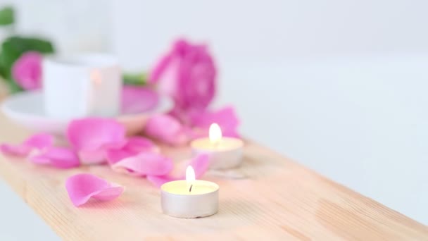 Bella cornice termale con candela rosa e fiori su sfondo di legno. Concetto di trattamento termale nel salone. Atmosfera di relax, serenità e piacere. Stile di vita di lusso. - Filmati, video