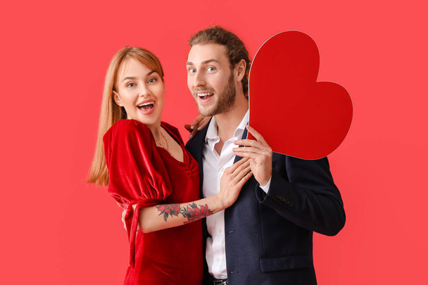 Mladý pár s červeným srdcem na pozadí barvy. Valentýnská oslava - Fotografie, Obrázek