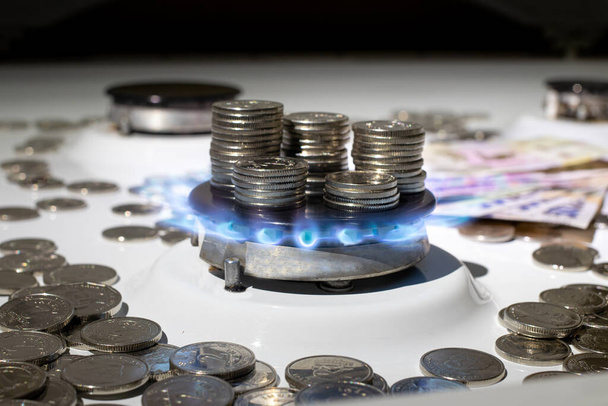 Moneda ucraniana hryvnias y una columna de gas con fuego. El precio del gas en Ucrania, en el contexto de las facturas de hryvnia ucraniana - Foto, imagen