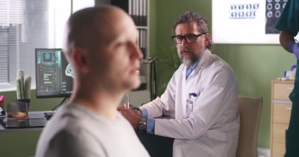 Uomo calvo che parla con l'oncologo durante la vaccinazione - Filmati, video
