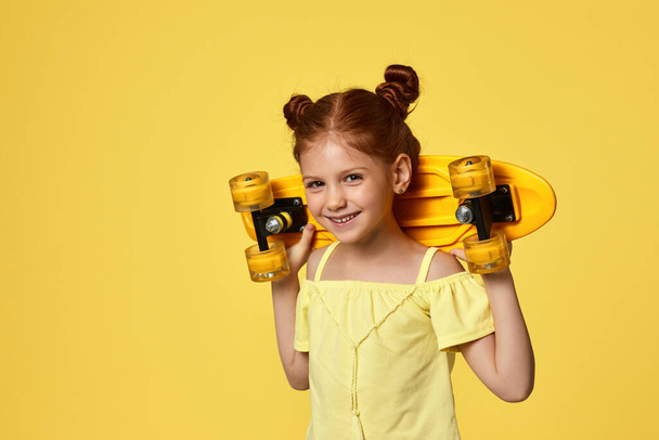 little child girl with yellow skateboard - Foto, afbeelding