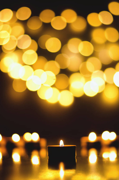 Płonące świece z świątecznym bokeh na czarnym tle. Koncepcja święta. Koncepcja modlitwy i nadziei. - Zdjęcie, obraz