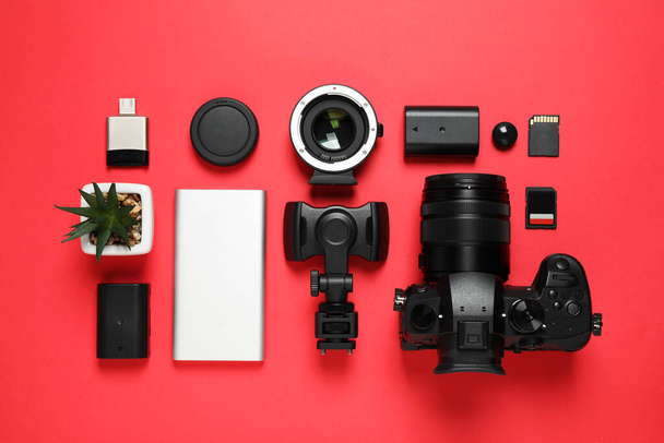 Flat lay composition with camera and video production equipment on red background - Фото, изображение