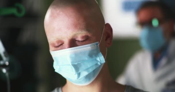 Расстроенный онкологический пациент в маске смотрит вниз - Кадры, видео