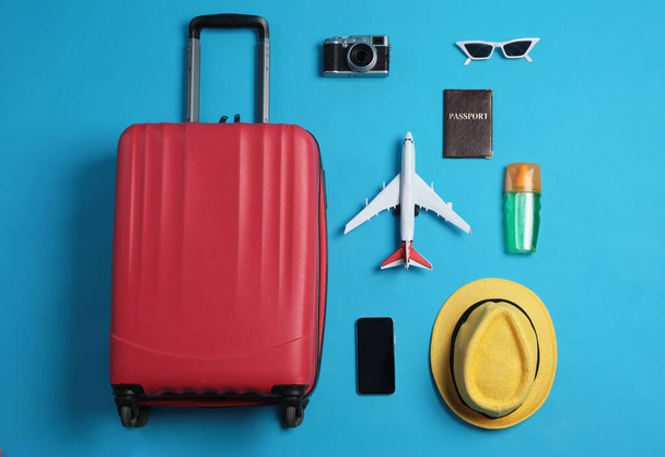 Flat lay composition with suitcase and travel accessories on light blue background. Summer vacation - Foto, imagen