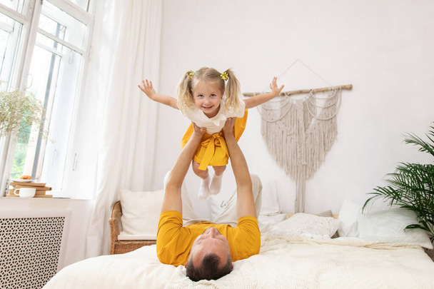 Father and his daughter child girl playing together. Dad's holding his daughter in his arms. parent lifts the girl high - Foto, afbeelding