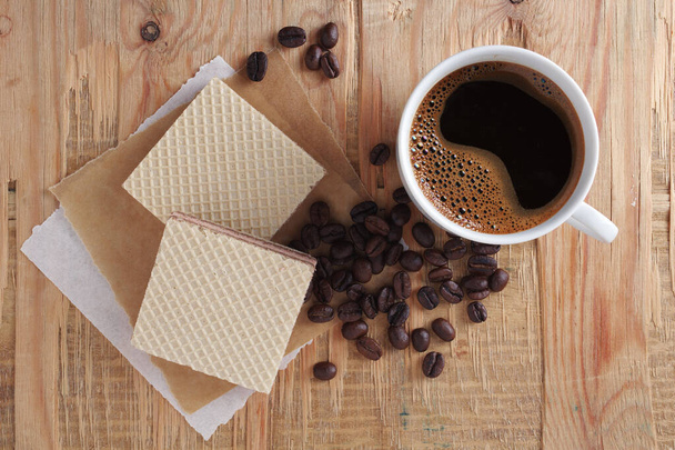 Wafers with filling and cup of coffee on old wooden background, top view - Fotografie, Obrázek