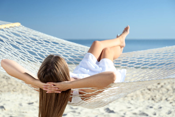 Young woman relaxing in hammock on beach - Фото, зображення
