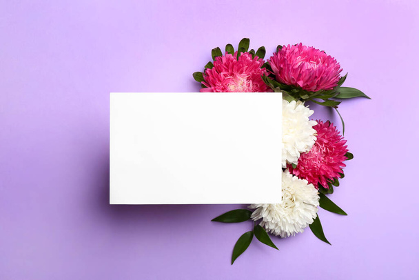 Flat lay composition with blank card and beautiful asters on lilac background, space for text. Autumn flowers - Foto, Imagem