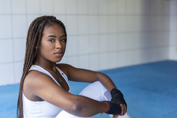 Portrait of beautiful afro black girl looking at camera sitting to train inside a gym. - Photo, Image