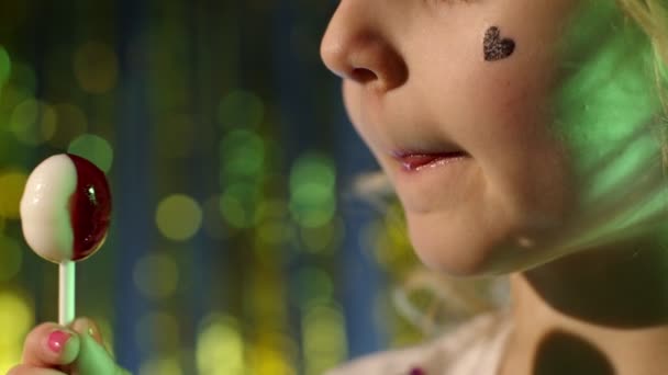 close-up shot van stijlvolle tiener Kaukasisch kind meisje lippen likken lolly met tong, slow motion - Video