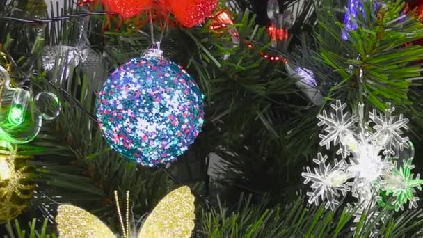 Sobre un fondo gris, primer plano de decoraciones brillantes en un árbol de Navidad - Metraje, vídeo