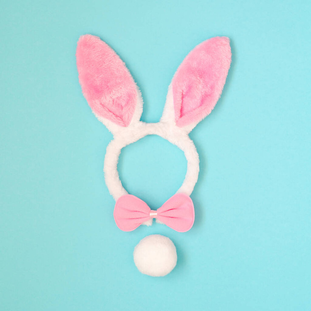 Easter holiday background with pink bunny ears, bow on a blue background. Top view - Фото, изображение
