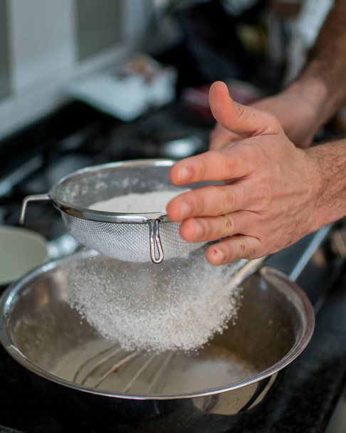 Unrecognizable hands straining flour for carrot cake preparation - Foto, Imagen