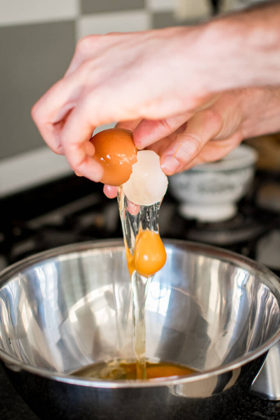 Manos irreconocibles agrietando huevos para la preparación del pastel de zanahoria - Foto, imagen