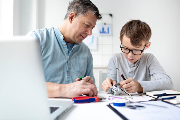 Father and son repairing an electrical outlet while sitting at a desk. Learn for life concept - Foto, Imagen
