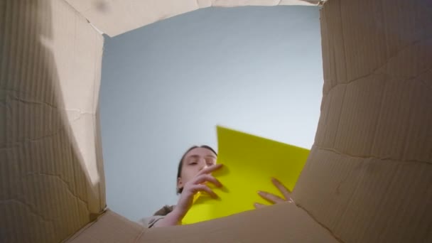 Film kobiety rzucającej pogniecionym żółtym papierem, widok z dołu - Materiał filmowy, wideo