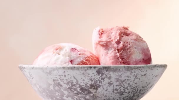 close-up van twee roze fruit ijsballen in een schaal draaien op beige achtergrond - Video