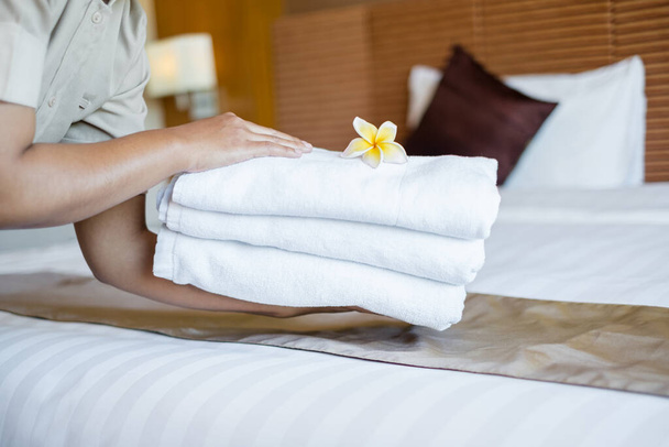 A hotel maid stacked towels on the bed and placed flowers on the towels in a hotel room. - Foto, Imagem