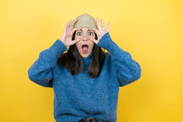 Young beautiful woman wearing blue casual sweater and wool hat Trying to open eyes with fingers, sleepy and tired for morning fatigue - Foto, Imagen