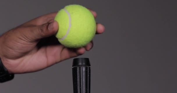 Μια κομψή πράσινη μπάλα του τένις στερεωμένη σε μαύρο ραβδί. Μπάλα του τένις εξισορρόπηση σε ένα ραβδί - Πλάνα, βίντεο
