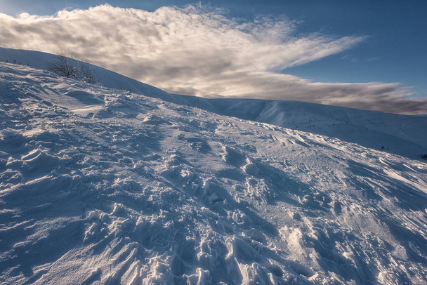 Niesamowity zimowy krajobraz ze świeżym puszystym śniegiem na zboczach gór i błękitnym niebem z chmurami, plenerowe tło podróży, Karpaty, Zakarpattia, Ukraina - Zdjęcie, obraz